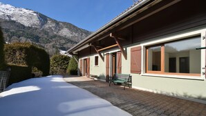 Un edificio con il terreno innevato, persiane di legno e una panchina all'esterno.