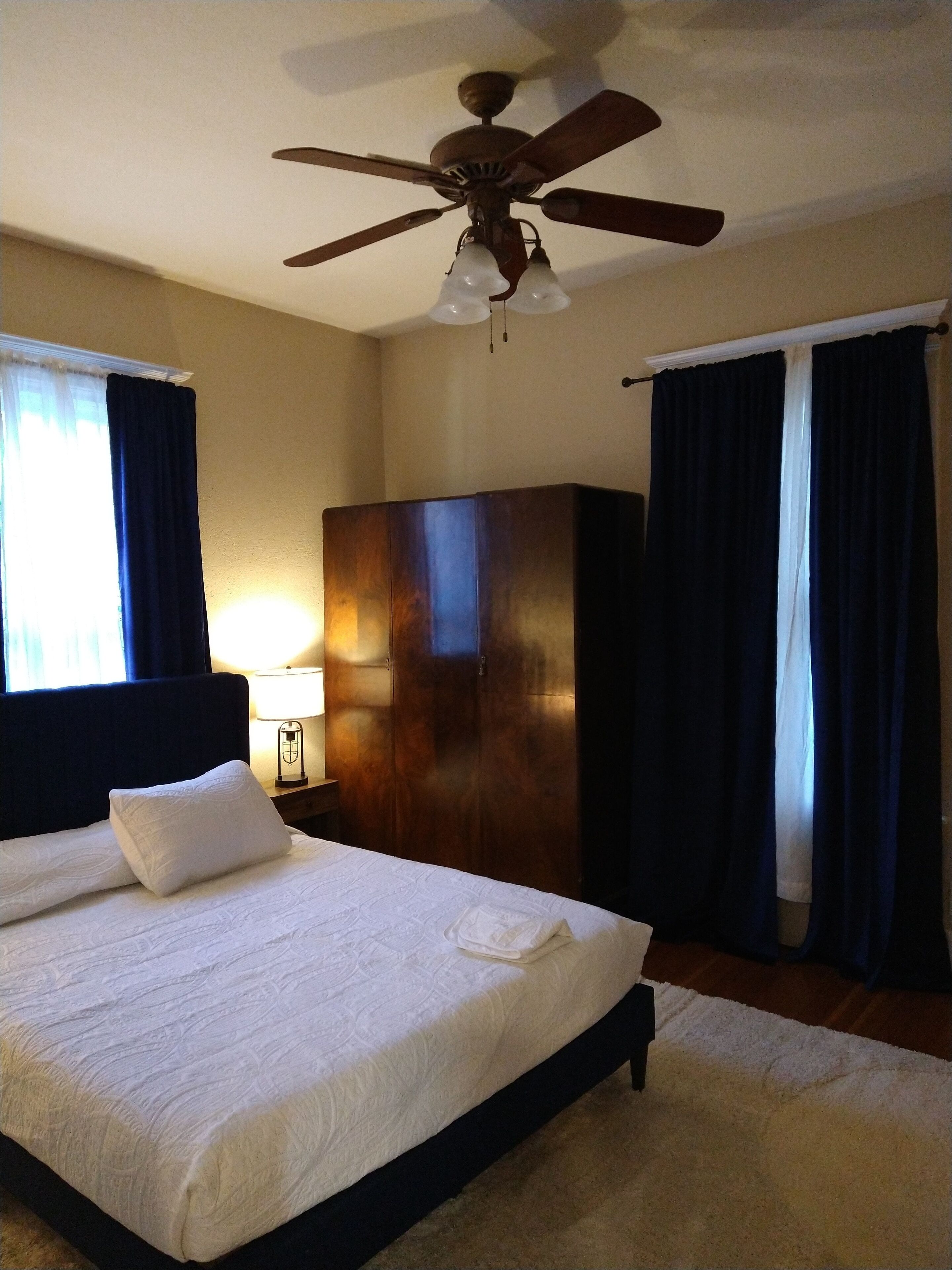 Una habitación de hotel con una cama grande, un ventilador de techo y un armario.