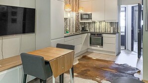 A modern kitchen with white cabinets, a wooden dining table, and a cowhide rug. - Amazing apartment in Bjorli with WiFi (Bjorli)