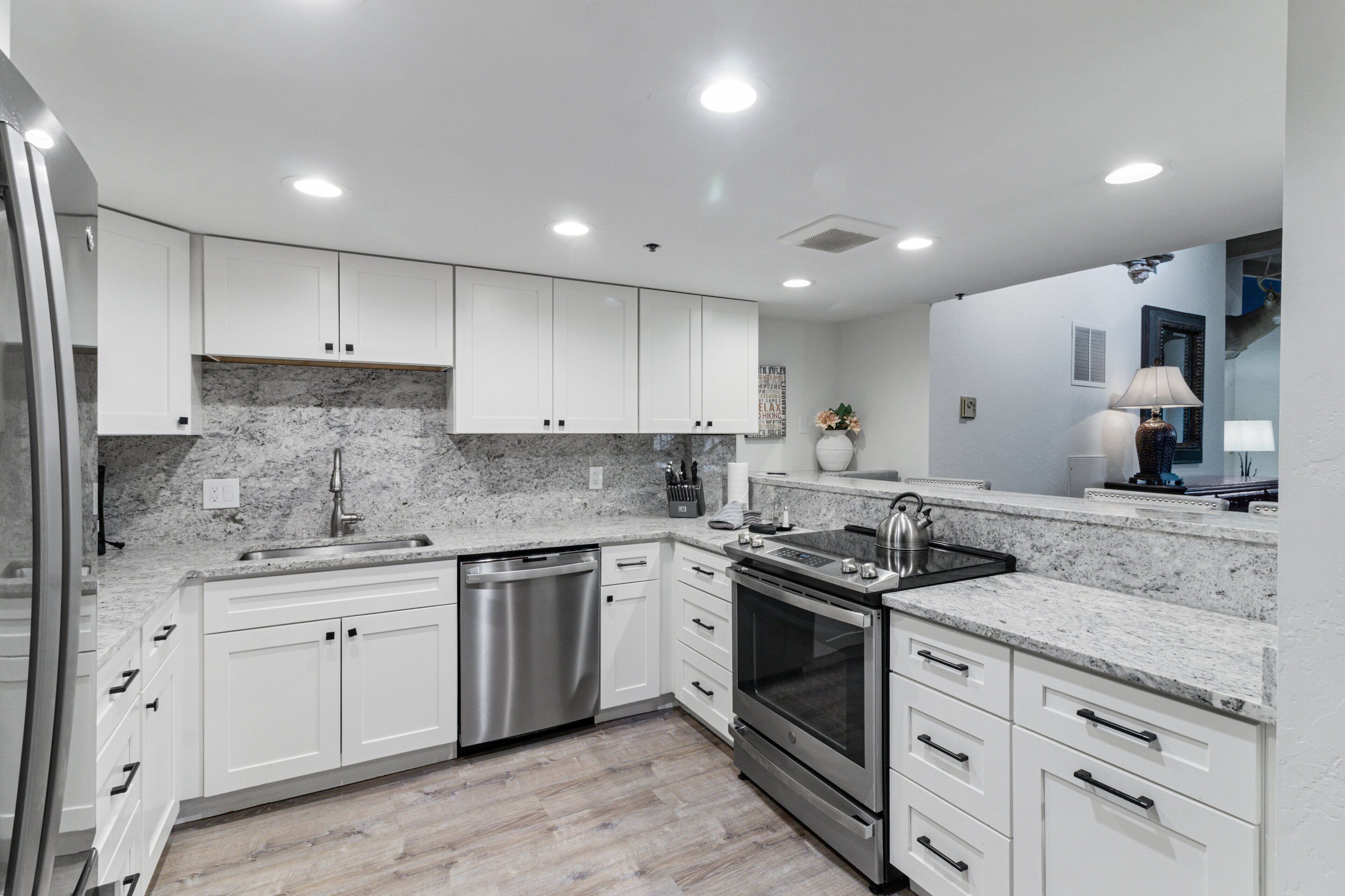 A modern kitchen with white cabinets, stainless steel appliances, and a granite countertop.