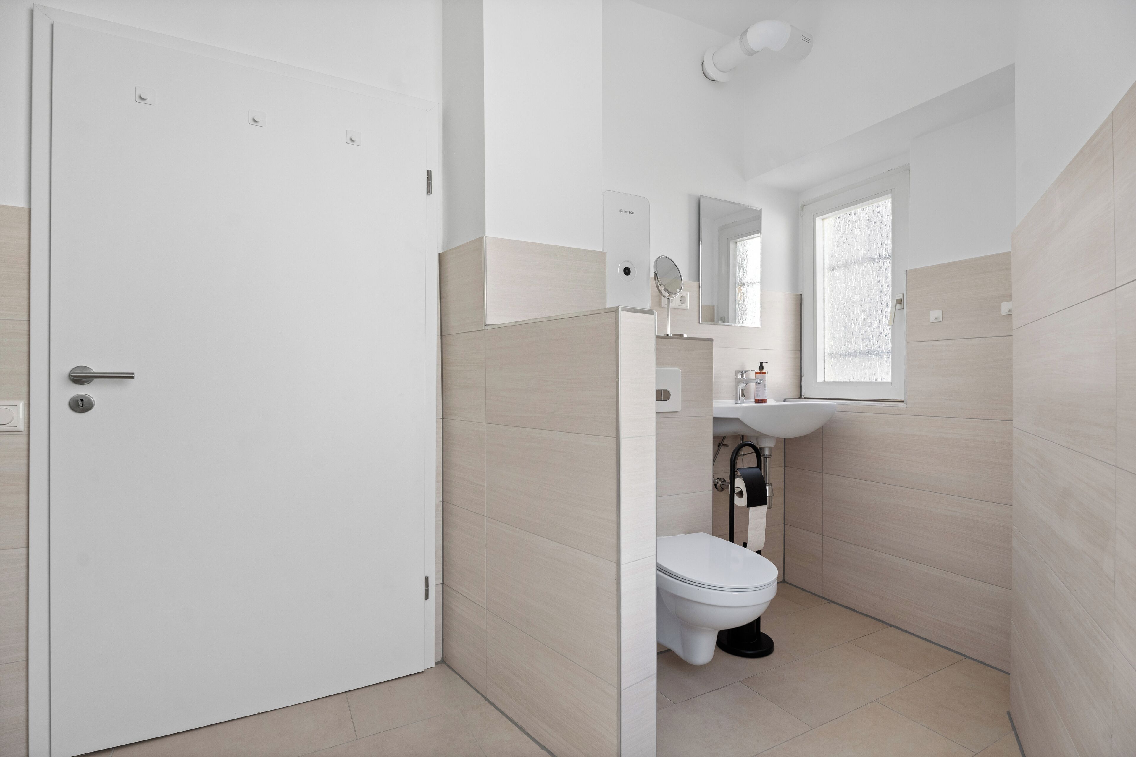 Un baño moderno con inodoro, lavamanos y espejo.