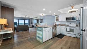Una cocina moderna con armarios blancos, microondas integrado y refrigerador de acero inoxidable.