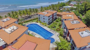 A resort with a swimming pool, beach view, and multiple buildings with red roofs.