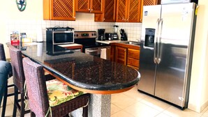 A kitchen with wooden cabinets, a microwave, a stove, a refrigerator, and a coffee maker.