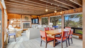 A spacious living area with a wooden ceiling, a dining table with chairs, a sofa, and a television. - House 25 | 4 Bedroom (Watsonville)