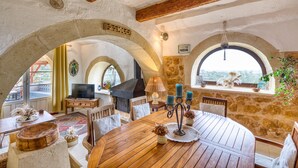 Un interior rústico con una mesa de comedor de madera, paredes de piedra y techos abovedados.