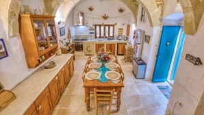 Una cocina rústica con arcos de piedra, armarios de madera y una mesa de comedor preparada para seis personas.
