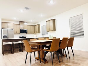 Eine moderne Küche mit Holzschränken, einem Edelstahlkühlschrank und einem Essbereich mit Holztisch und Stühlen.