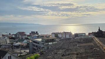 A coastal cityscape with a view of the sea and distant mountains.