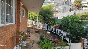 A residential property with a brick exterior, a covered porch, and a garden area with a white fence. - Reñaca Village, in Viña del Mar, 3 min walking to beach, @casavista_panoramica (Viña del Mar)