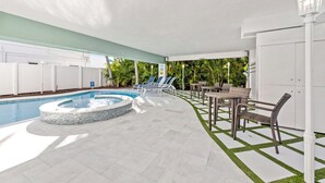 Ein Poolbereich mit Whirlpool, Liegestühlen und Essbereich mit Tischen und Stühlen.