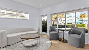 A modern living room with a white sofa, a round coffee table, and two grey armchairs. - Beachside Bliss • Renovated Studio • Walk to Ocean & Restaurants + Saltwater Pool (Fort Lauderdale)