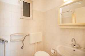 Une salle de bain avec des toilettes, un lavabo et un miroir.