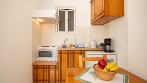 A compact kitchen with wooden cabinets, a microwave, a coffee maker, and a table with a fruit basket. - Corfu apartment with shared pool near Saint Spyridon beach (Saint Spyridon)