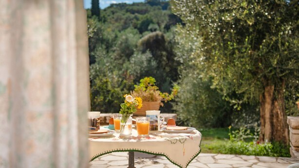 A table set outdoors with a view of a lush garden and trees. - Corfu apartment with shared pool near Saint Spyridon beach (Saint Spyridon)