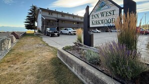 A hotel named 'Inn West Kirkwood' with a parking lot, a building with multiple windows, and a clear sky. - Summit View II Bed & Bath| Ski-In Hot Tub Sleeps 2 (Kimberley)