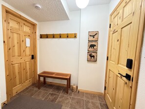 A hallway with wooden doors, a bench, and wall-mounted hooks. - Summit View II Bed & Bath| Ski-In Hot Tub Sleeps 2 (Kimberley)