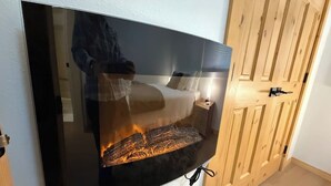 A flat-screen TV mounted on a wall with a wooden door to the right. - Summit View II Bed & Bath| Ski-In Hot Tub Sleeps 2 (Kimberley)
