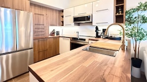 Une cuisine moderne dotée d’appareils électroménagers en acier inoxydable, de meubles en bois et d’un îlot central avec un évier.