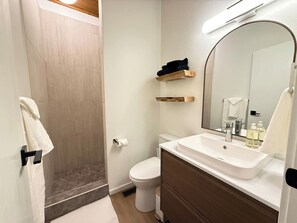 A bathroom with a shower, toilet, sink, and mirror.