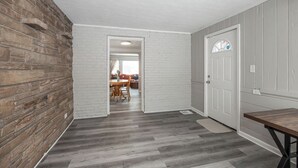 Ein Flur mit Backsteinwand, weißen Wänden und Holzboden.