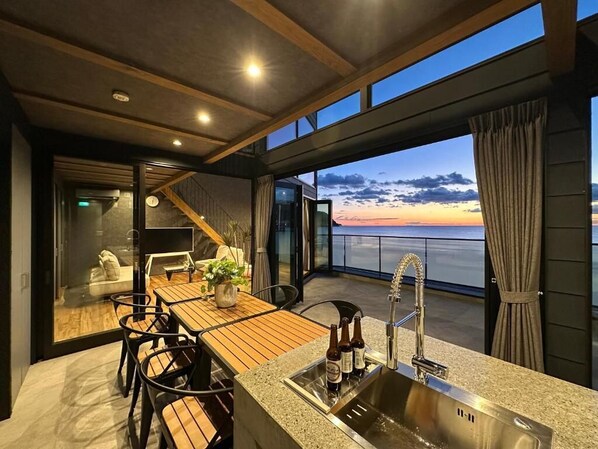A modern kitchen with a wooden table, chairs, and a sink. - VILLA IZU Zessei (Ito)