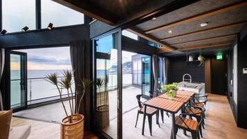 Un interior moderno con zona de comedor, ventanas amplias y vista al mar.