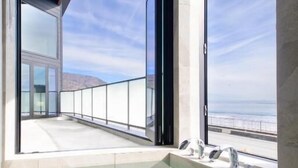 A modern indoor pool with glass walls and a view of the ocean. - VILLA IZU Zessei (Ito)