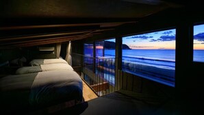A room with a bed and a large window overlooking the ocean at sunset. - VILLA IZU Zessei (Ito)