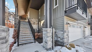 En bostadsbyggnad med en fasad av sten, en trätrappa och ett garage.