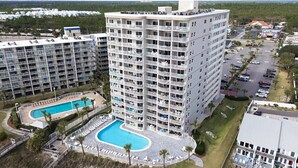 Un hotel di grandi dimensioni con numerosi balconi, una piscina e un’area parcheggio.