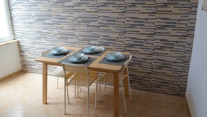 Comedor con una mesa lista para cuatro personas, cuatro sillas y un papel tapiz decorado.