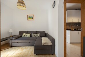 Un soggiorno moderno con un divano ad angolo grigio, un tavolino con una lampada, un lampadario e un quadro appeso al muro.