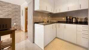 Una cocina moderna con armarios blancos, encimera negra y horno empotrado.