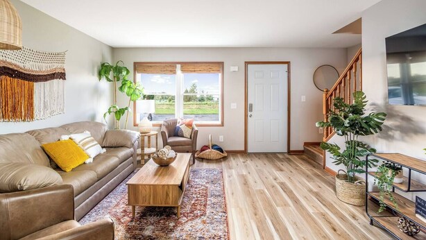 Ein Wohnzimmer mit Sofa, Couchtisch und Blick ins Freie durch große Fenster.