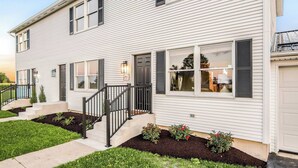 Ein zweistöckiges Haus mit Veranda, Treppe und Garage.