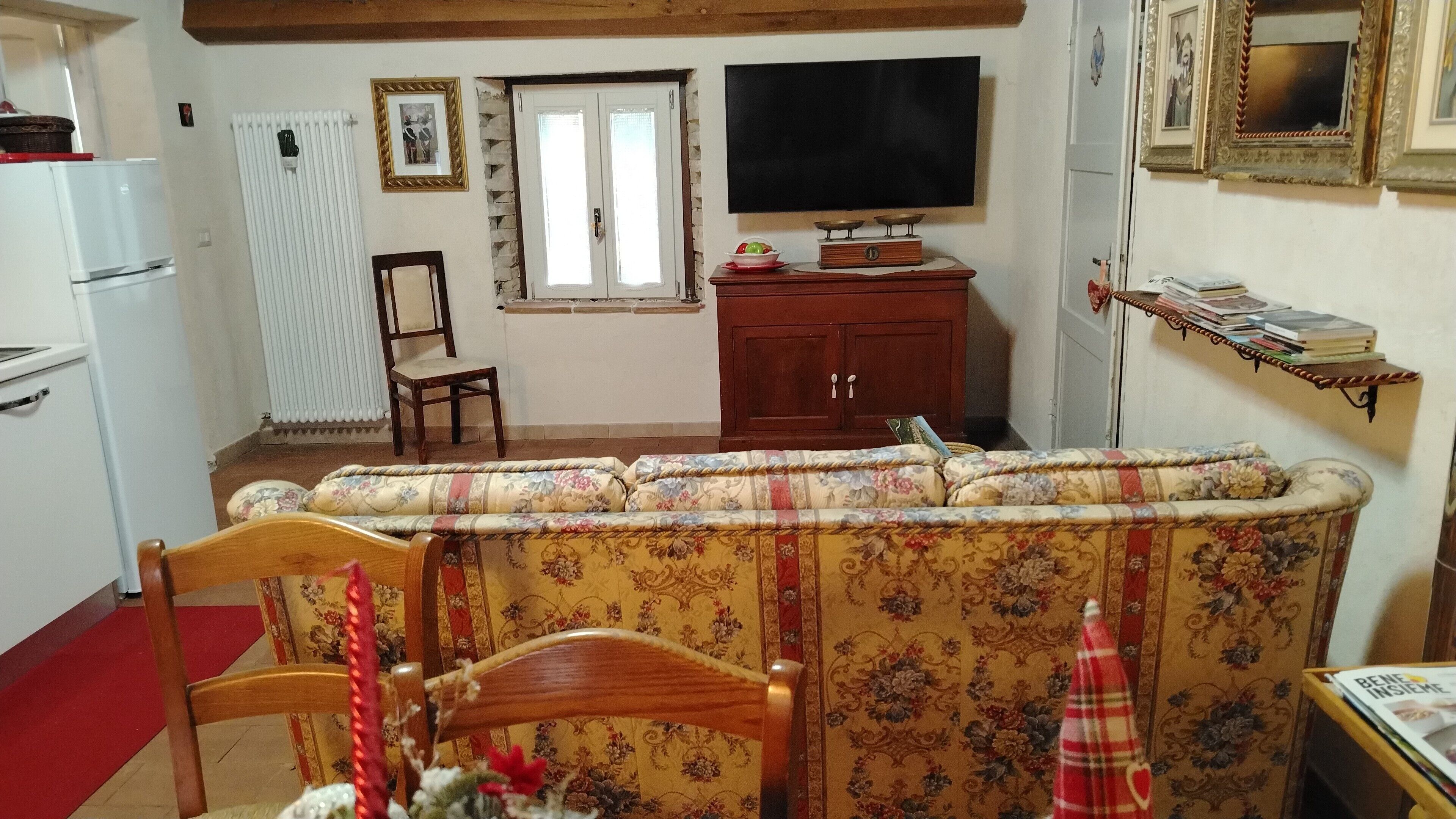 A living room with a sofa, a television, a wooden cabinet, and a dining area with a table and chairs.