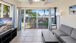 A living room with a TV, a sofa, a coffee table, and a ceiling fan. - Ground floor, updated studio, across from the beach! - Kihei Bay Surf A101 (Kihei)