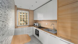 A modern kitchen with white cabinets, a wooden countertop, and a window overlooking a cityscape. - Nowa Huta Charming Apartment (Kraków)