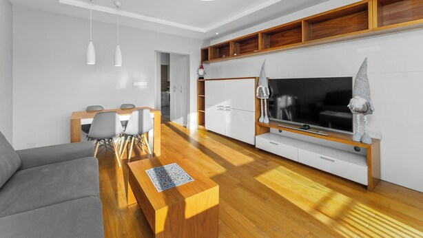 A modern living room with a sofa, coffee table, TV, and wooden flooring. - Nowa Huta Charming Apartment (Kraków)