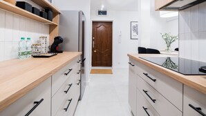 A modern kitchen with wooden countertops, white cabinets, and a built-in refrigerator. - Krakowska Downtown Deluxe Apartment (Poznań)