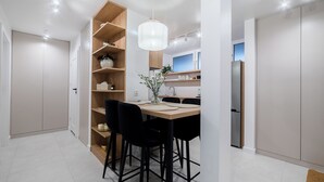 A modern kitchen with a wooden island, black chairs, and a hanging light fixture. - Krakowska Downtown Deluxe Apartment (Poznań)