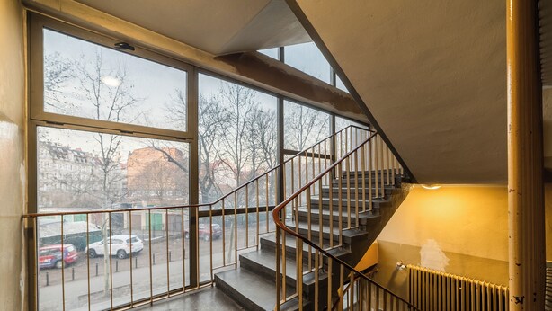 A staircase with metal railings leading to a landing with a radiator. - Krakowska Downtown Deluxe Apartment (Poznań)