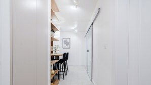 A narrow hallway with a dining area featuring a table and chairs, a plant on the shelf, and a framed picture on the wall. - Krakowska Downtown Deluxe Apartment (Poznań)