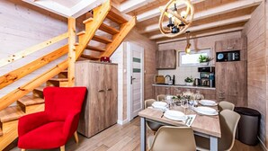 Une cuisine compacte avec des meubles de rangement en bois, une table à manger pour quatre personnes et une chaise rouge.