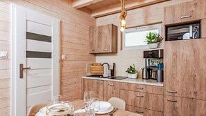 Une cuisine compacte avec des meubles en bois, un four à micro-ondes encastré et un petit coin repas avec une table dressée pour deux personnes.