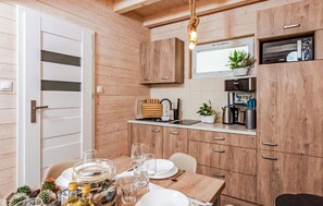 Eine kompakte Küche mit Holzausstattung, einer eingebauten Mikrowelle und einer kleinen Essecke mit Tisch für zwei Personen.