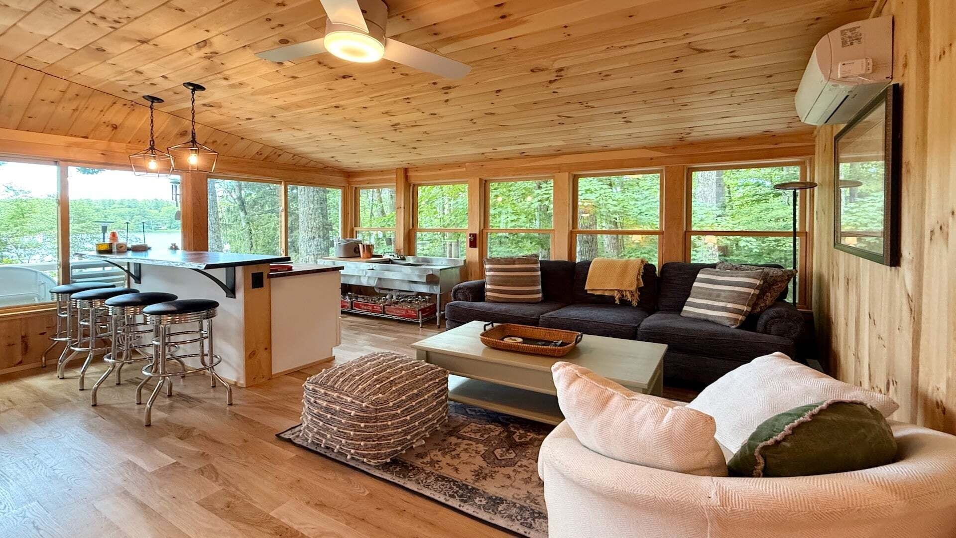 A wooden cabin interior with a kitchen, dining area, and living room.