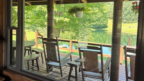 Une terrasse en bois, dotée de mobilier d’extérieur et offrant une vue sur un lac.