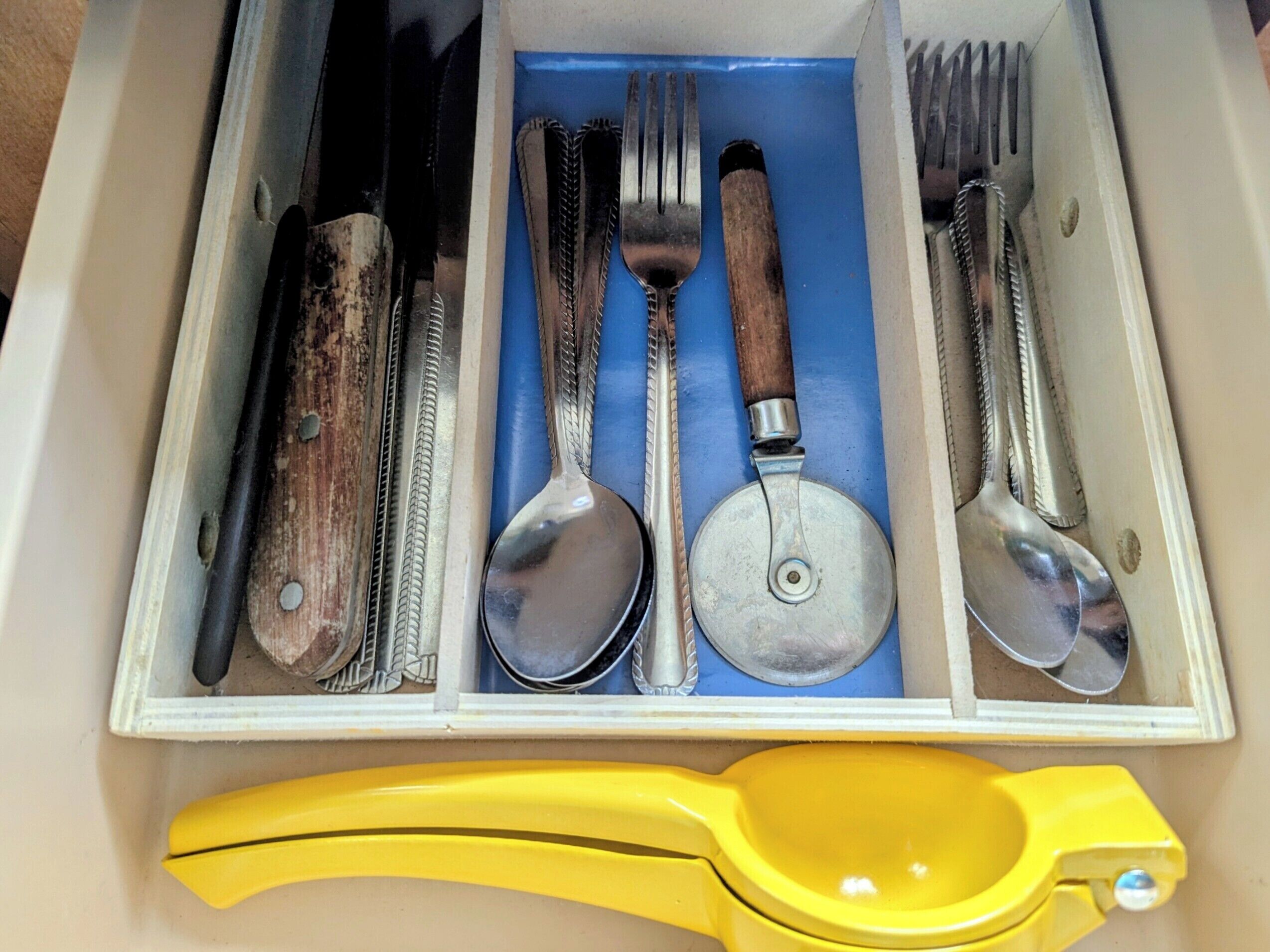 Un cajón con un cuchillo, un tenedor, una cuchara y un abrelatas.